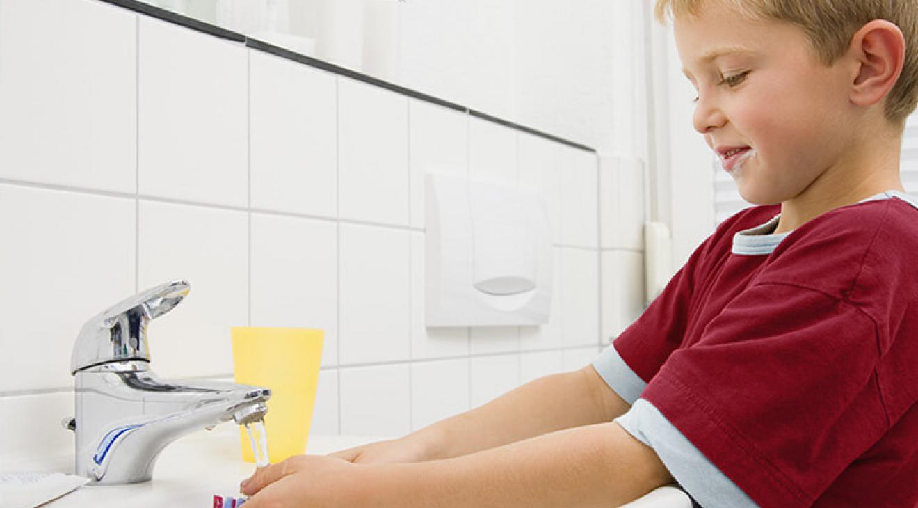 Un enfant en train de se laver les mains dans un lavabo